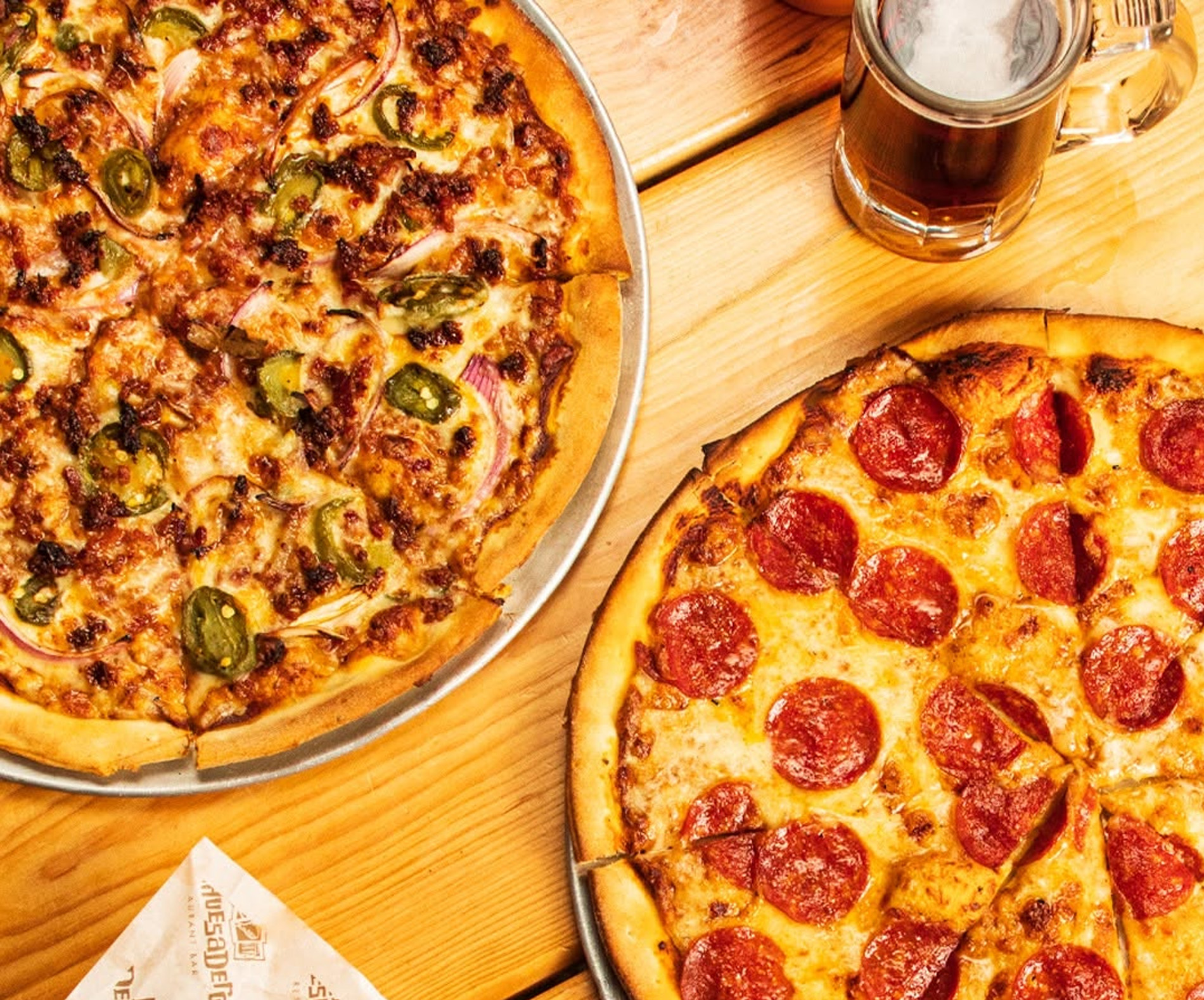 Pizzas de pepperoni y jalapeño con un tarro de cerveza